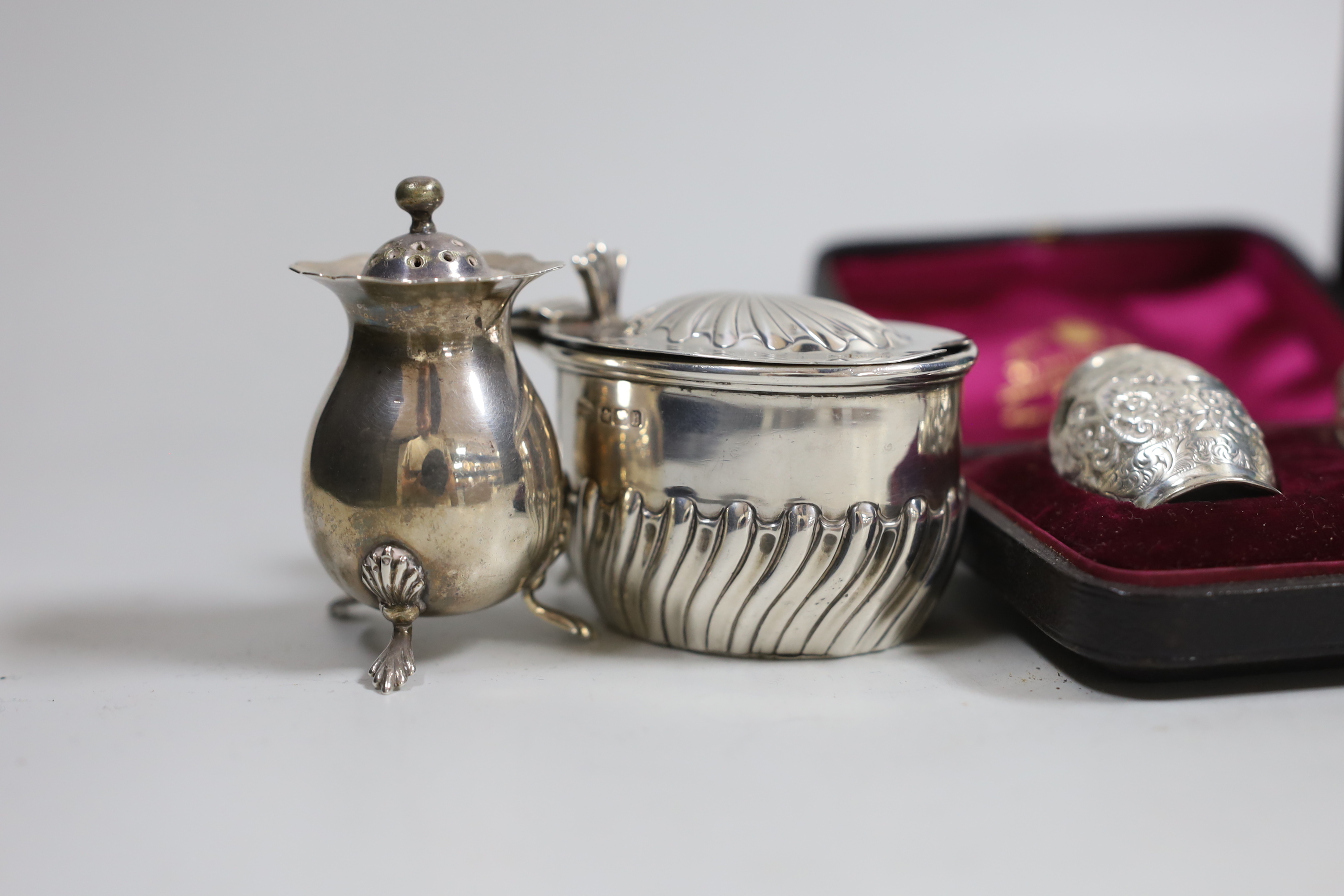 Two cased pairs of silver condiments including chased pepperettes, 45mm and four other silver condiments.